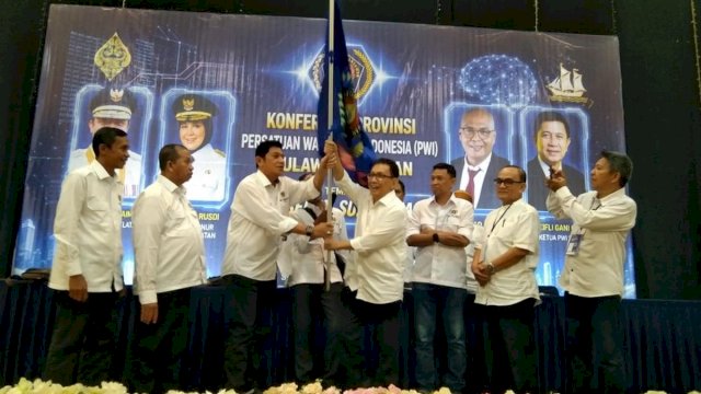 KETUA TERPILIH. Suwardi Thahir mengibarkan bendera PWI usai terpilih sebagai Ketua PWI Sulsel periode 2026-2031 pada Konferprov PWI Sulsel di Graha Pena, Kota Makassar, Selasa (2/6/2026). foto: YSR 